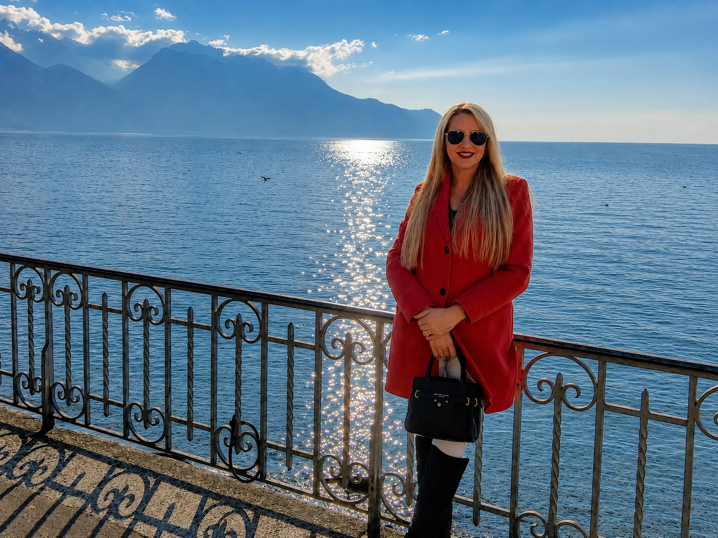 Deb overlooking Lake Geneva in Montreux, Switzerland, with the Swiss Alps and sparkling lake in the background.