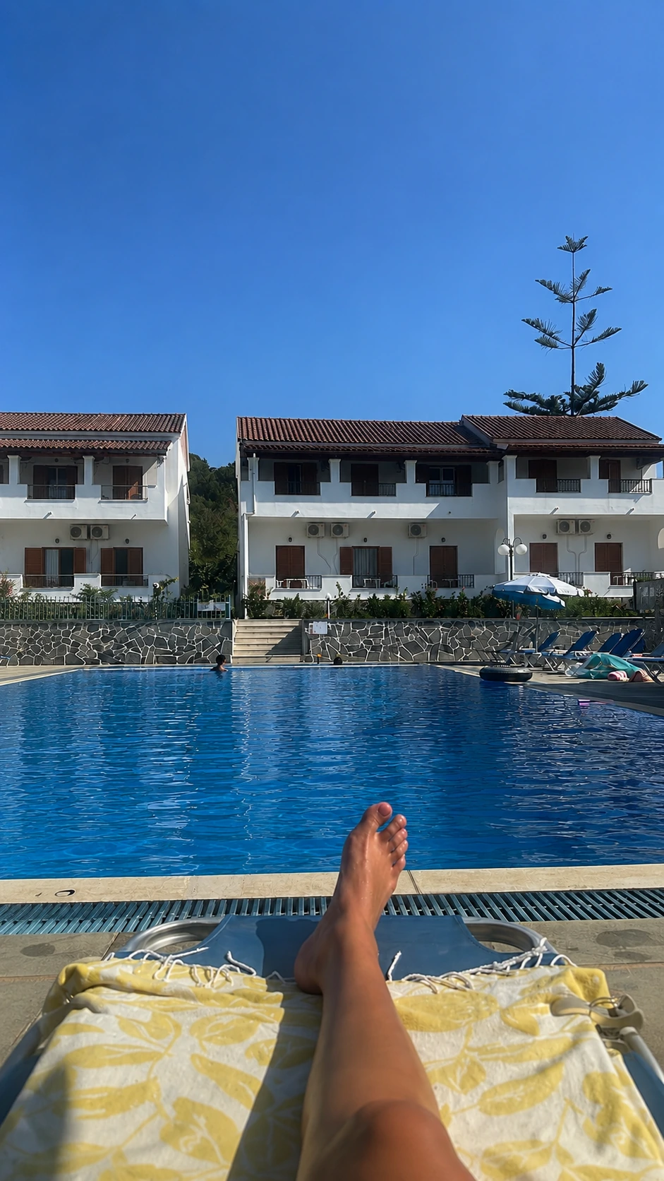 Relaxing poolside at Tria Adelphia in Arillas, Corfu, overlooking the swimming pool and traditional Greek-style accommodation.